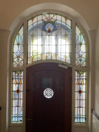 Houten voordeur met kleurrijk glas-in-loodraam in jugendstil-stijl aan de Oranje Nassaulaan.